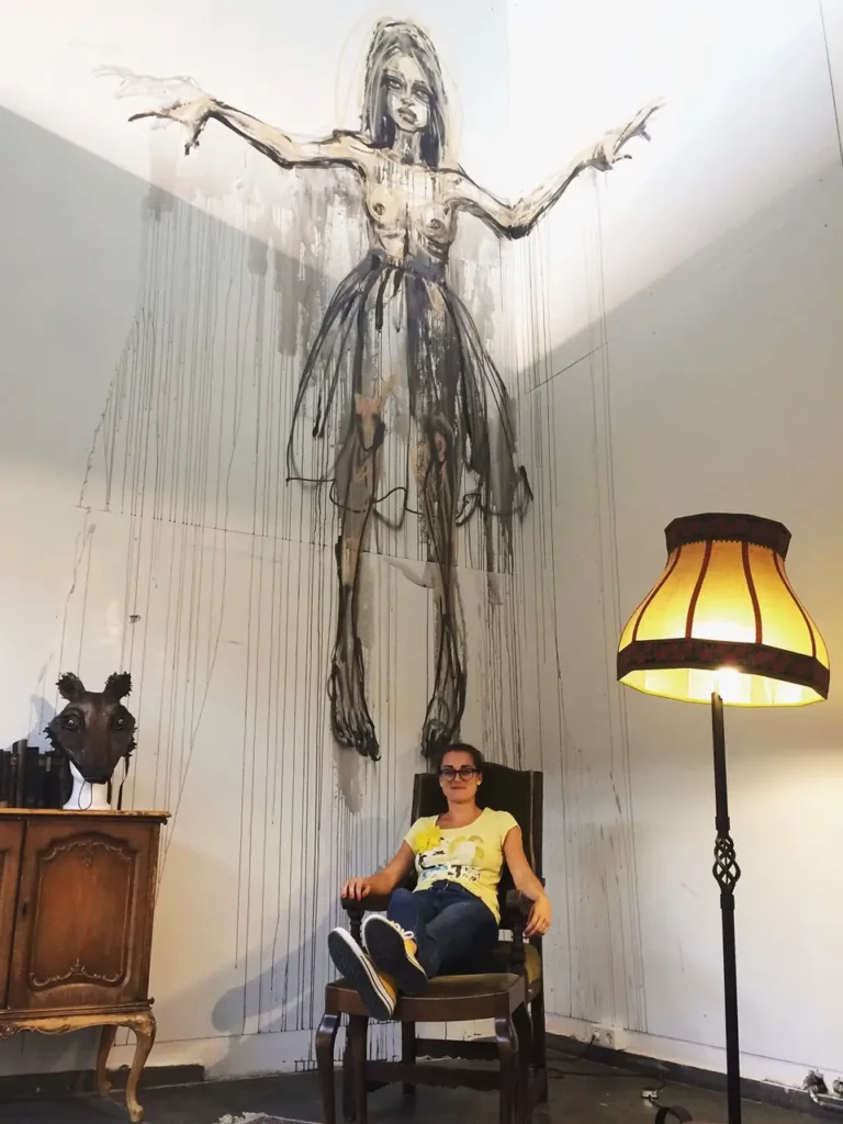 Frau sitzt vor einem Werk in der Herakut-Ausstellung im MUCA 2018